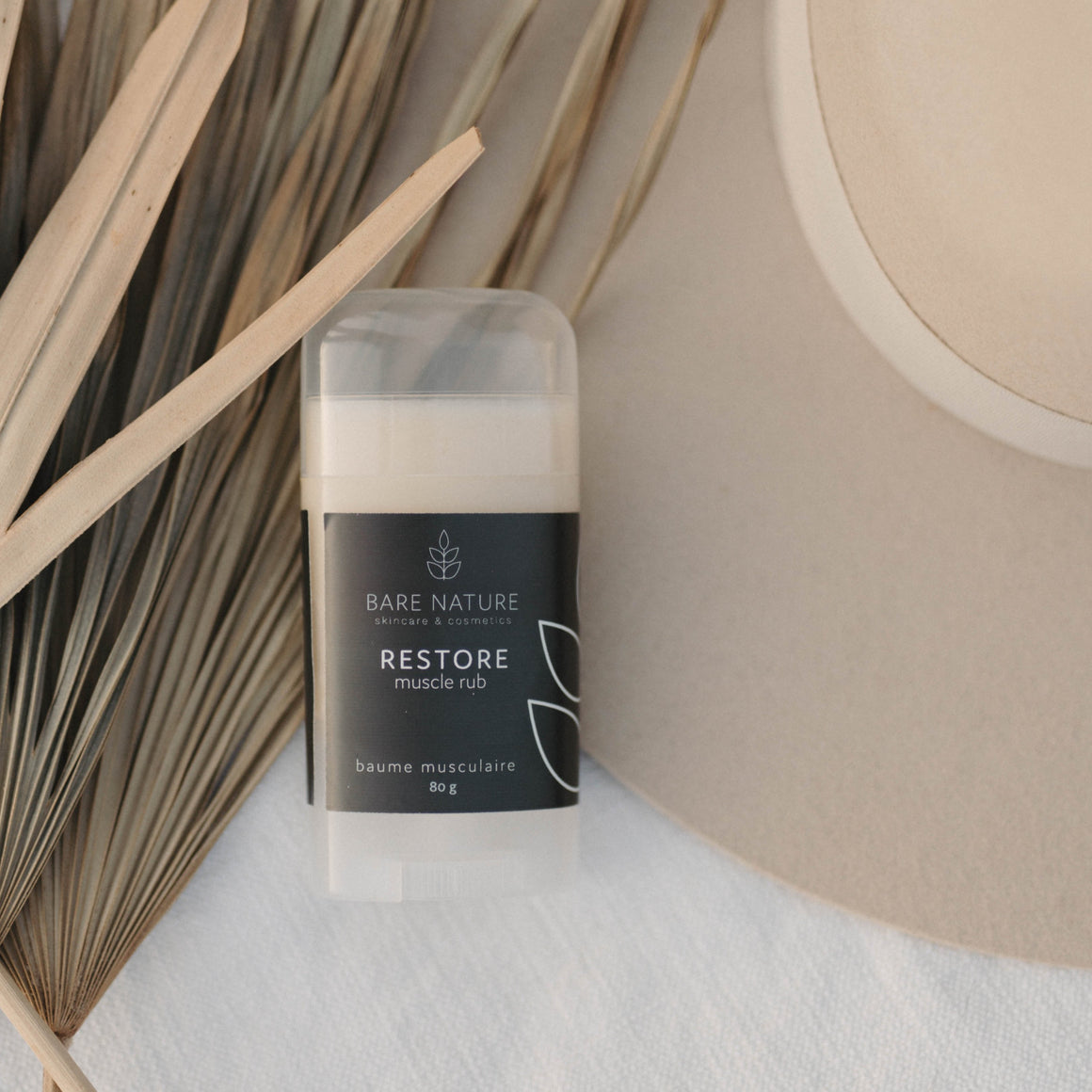 Muscle Rub Product on a background of dry palms and a felt hat. 